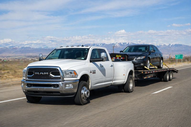 Pickup truck transporting a car on a flatbed trailer for hot shot trucking delivery